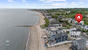 Une ville côtière avec des maisons donnant sur la plage, un ciel dégagé et une mer calme.