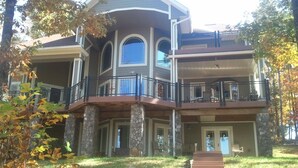 Une maison à deux étages avec des fondations en pierre, un balcon doté de balustrades noires et une porte d’entrée.