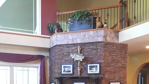 Un salon spacieux avec une cheminée en pierre, une grande fenêtre et un balcon agrémenté d’objets décoratifs.