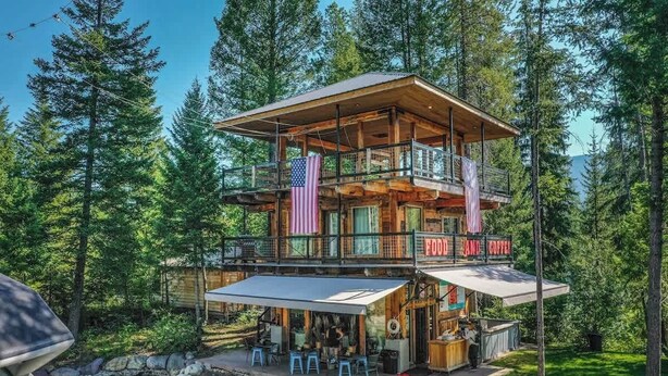 A multi-level cabin with a deck, a pool, and a sign advertising food and coffee.