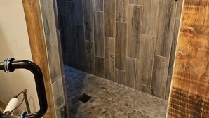 A shower area with a wooden floor and a showerhead.