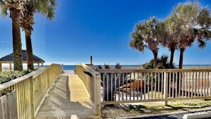 A wooden boardwalk leading to a beach with palm trees and a clear blue sky. - Beachfront Penthouse Located On The 9th Floor with Two Balconies & Low Host Fee (Gulf Shores)