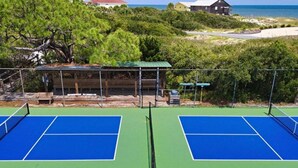 A tennis court with two courts, surrounded by greenery and a view of the sea. - Secluded 4BR/3.5BA, inside St. George Plantation (St. George Island)