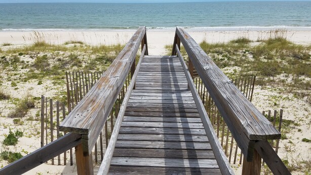 A wooden boardwalk leading to a beach with sand and sparse vegetation. - Secluded 4BR/3.5BA, inside St. George Plantation (St. George Island)
