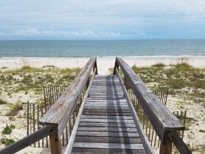 A wooden boardwalk leading to a beach with sand and sparse vegetation. - Secluded 4BR/3.5BA, inside St. George Plantation (St. George Island)