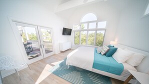 A bedroom with a bed, a TV, a window, and a balcony. - Secluded 4BR/3.5BA, inside St. George Plantation (St. George Island)