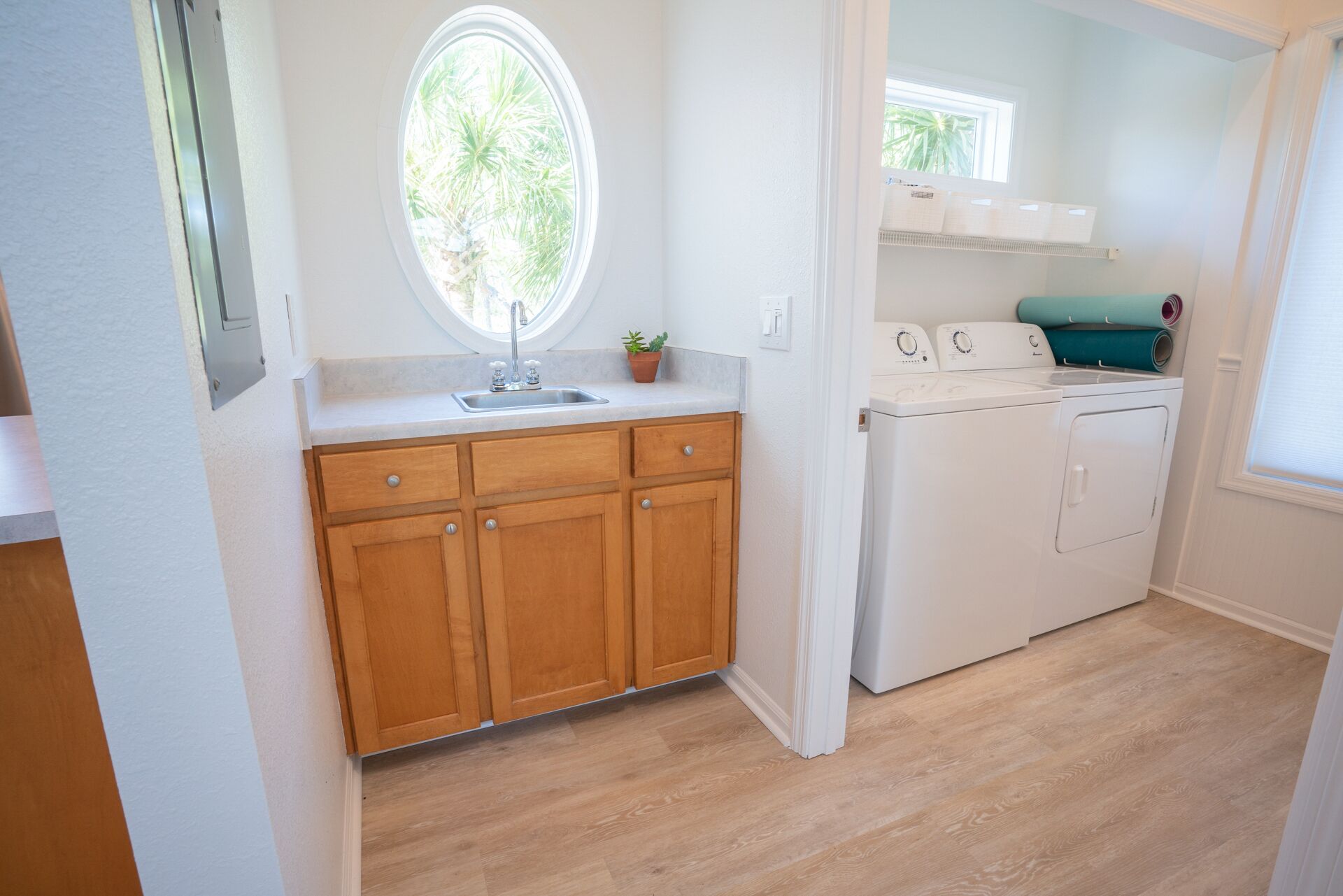 A laundry area with a washing machine, a sink, and wooden cabinets.