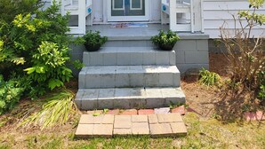 A white house with blue shutters, a front porch, and a sign reading "The Fishing Cottage."