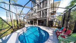 A modern pool area with a clear blue pool, surrounded by a glass enclosure, and colorful Adirondack chairs. - Bayfront, Handicap-Friendly, Pool & Elevator, Kayaks (St. George Island)