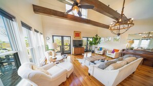 A spacious living room with white sofas, a wooden floor, and a ceiling fan. - Bayfront, Handicap-Friendly, Pool & Elevator, Kayaks (St. George Island)