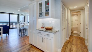Una cocina moderna con armarios blancos, piso de madera y vistas al exterior.