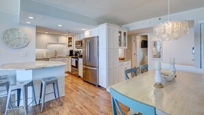 Una cocina moderna con armarios blancos, electrodomésticos de acero inoxidable y suelo de madera.