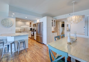 A modern kitchen with white cabinetry, stainless steel appliances, and a wooden floor.