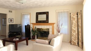 Una sala de estar con chimenea, televisor, sofá y mesa de centro.
