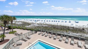 A pool area with lounge chairs and a view of the beach.