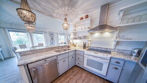 A modern kitchen with granite countertops, stainless steel appliances, and wooden flooring. - 3BR/2BA 1st Tier, Timeless Beauty w/ Easy Beach Access & Clubhouse w/ Pool! (St. George Island)
