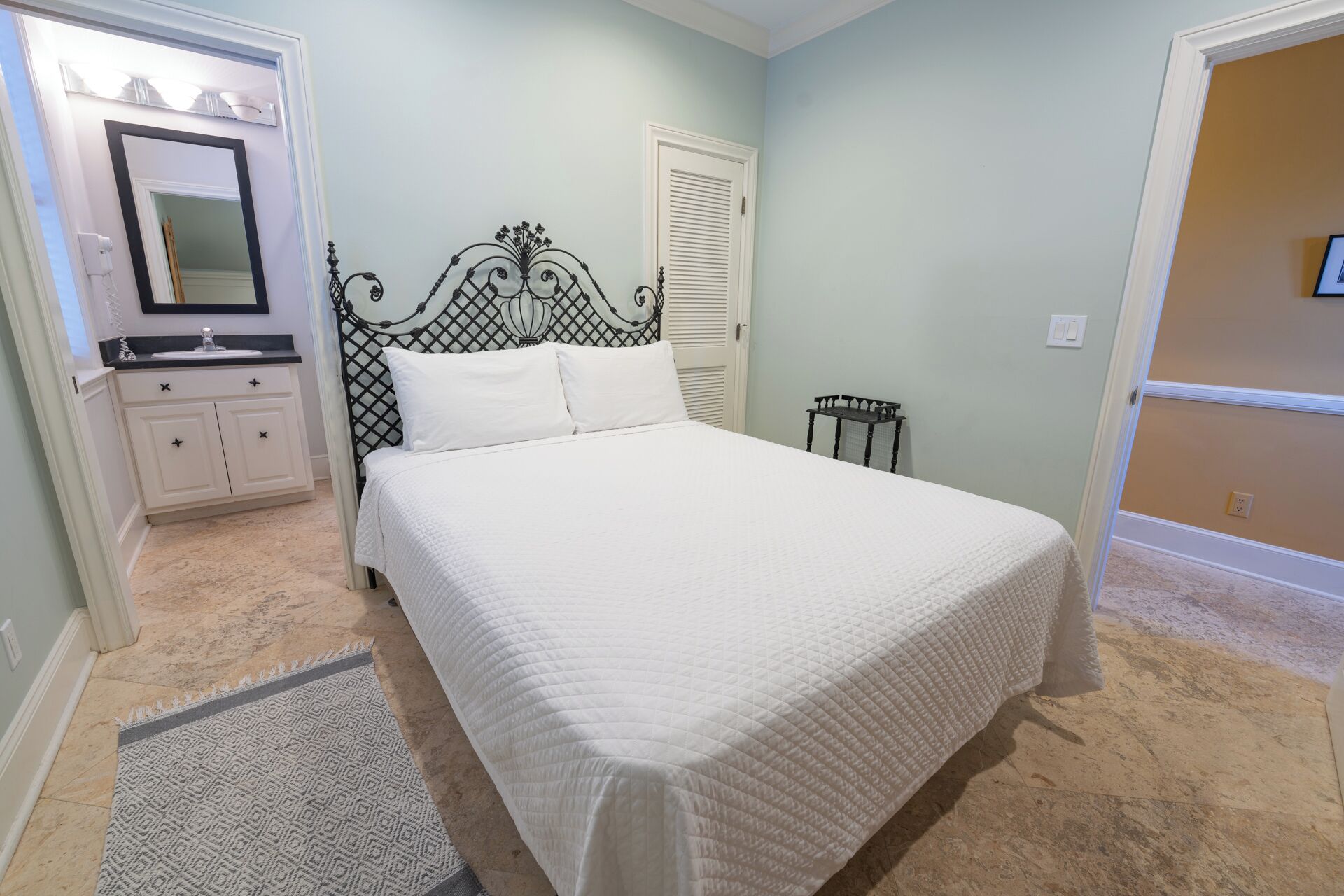 A bedroom with a bed, a dresser, a mirror, and a door.