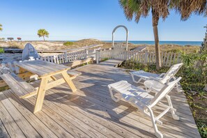 A wooden deck with picnic tables and white lounge chairs, overlooking a beach. - Pet Friendly, 3BR/3BA, Easy Walking Distance to Shops (St. George Island)