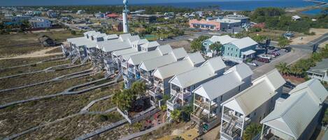 A coastal resort with multiple-story buildings, a lighthouse, and a beach access walkway.