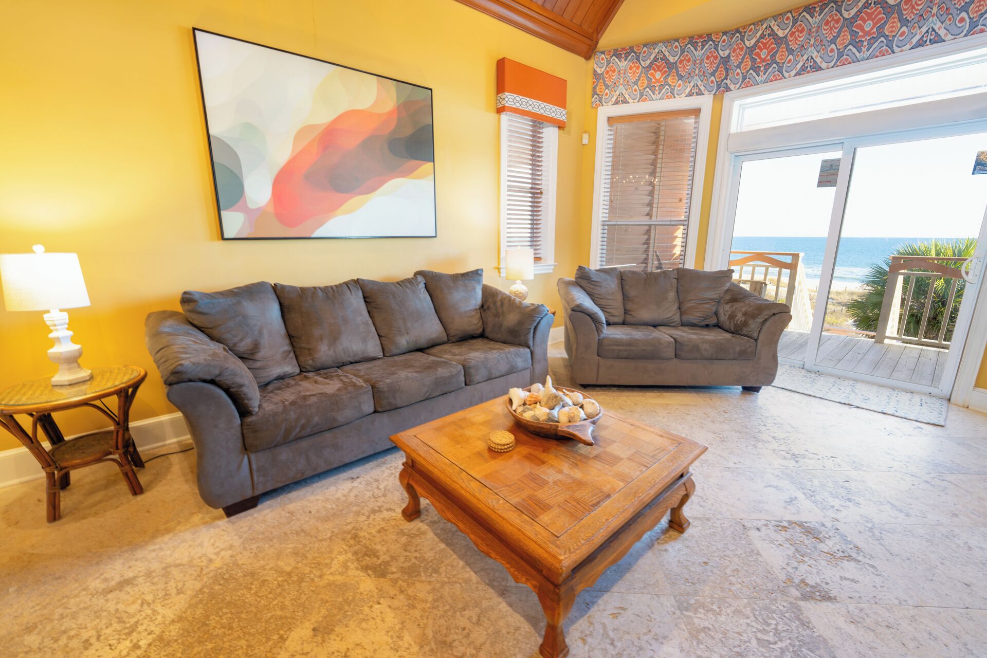 Ein Wohnzimmer mit zwei Sofas, einem Couchtisch und einem großen Fenster mit Blick auf das Meer.