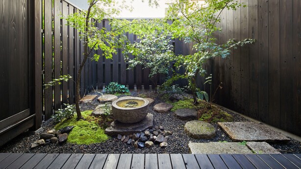 A wooden deck with a stone fountain, surrounded by rocks and moss. - Eigetsu (Kyoto)