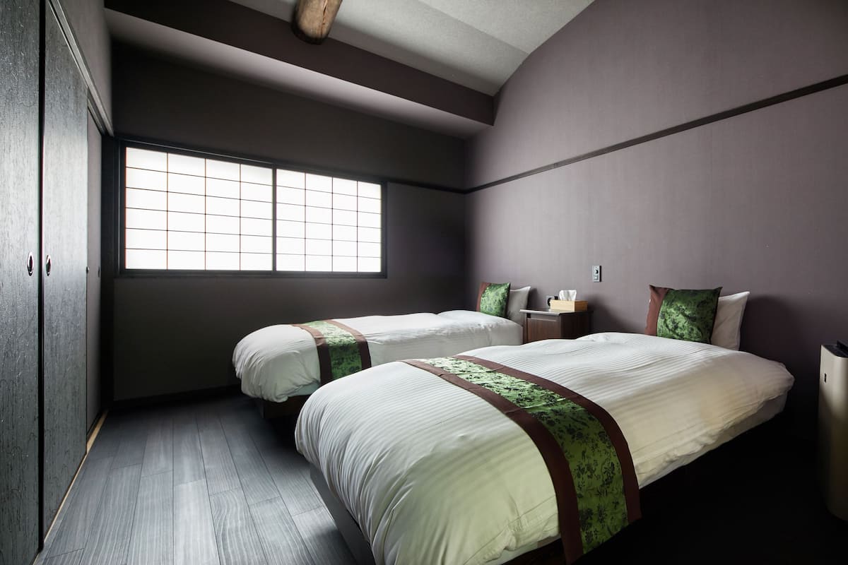 Ein Hotelzimmer mit zwei Betten, einem großen Fenster und Holzboden.