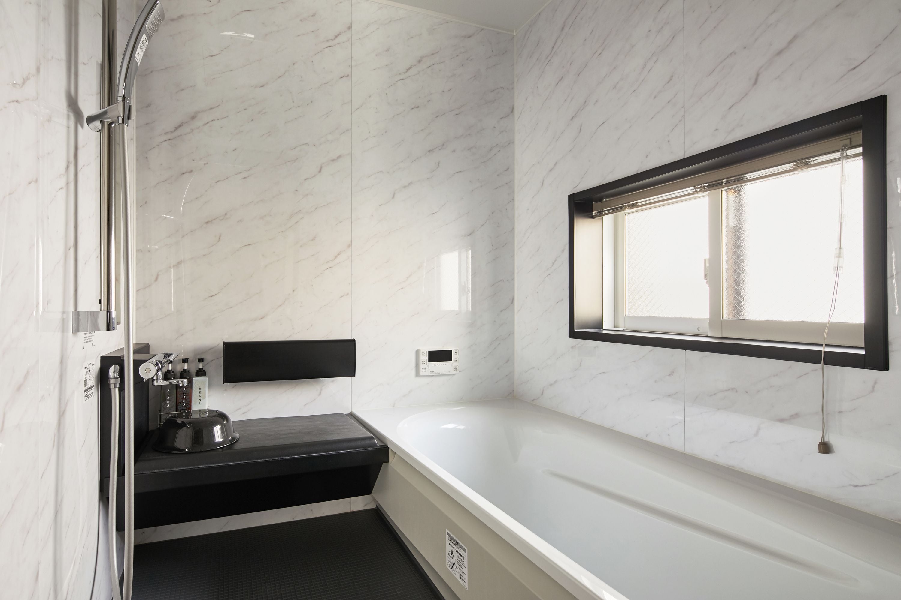 Une salle de bain avec un mur en marbre, une baignoire, une douche et une fenêtre.