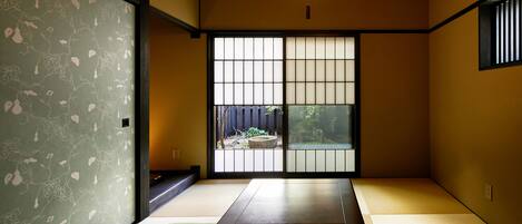 Una habitación japonesa tradicional con suelo de tatami, una mesa baja y puertas correderas.
