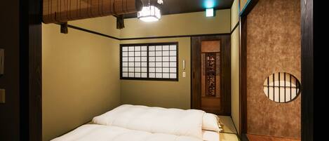 Una habitación tradicional japonesa con suelo de tatami, un panel shoji y una cama futón.