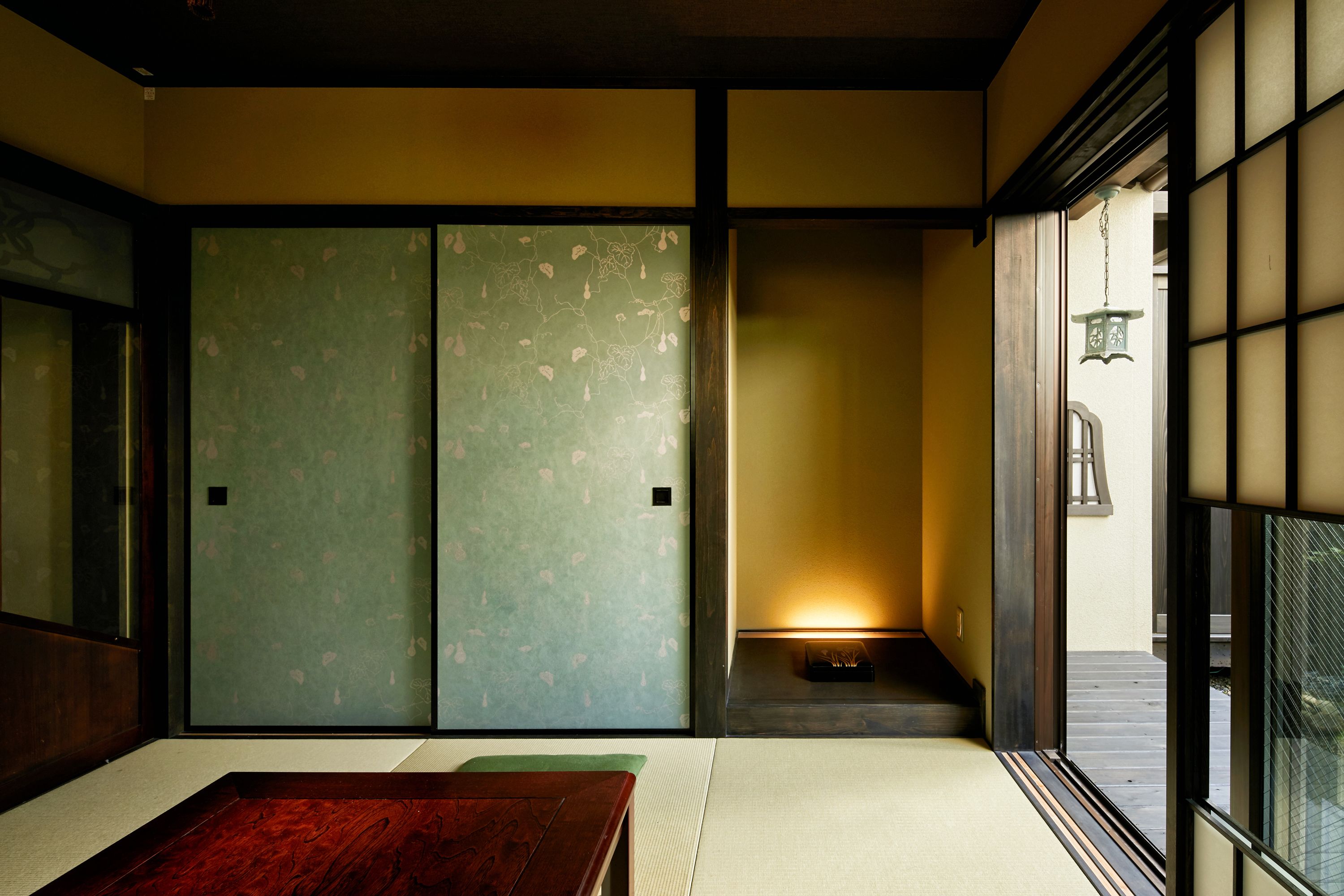 Una habitación tradicional japonesa con suelo de tatami, puertas correderas y una mesa de madera baja.