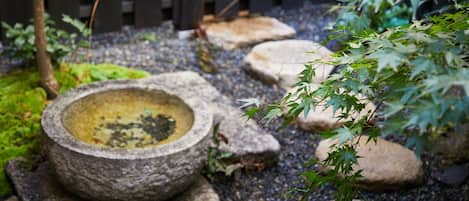 A stone birdbath surrounded by rocks and foliage in a garden setting.