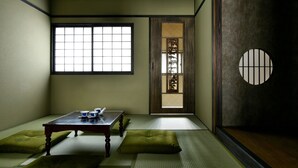A traditional Japanese room with tatami flooring, a low table with a tea set, and a sliding door with a decorative screen. - Eigetsu (Kyoto)