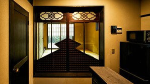 A staircase with a traditional design, leading to a room with a sliding door and a microwave on a counter. - Eigetsu (Kyoto)