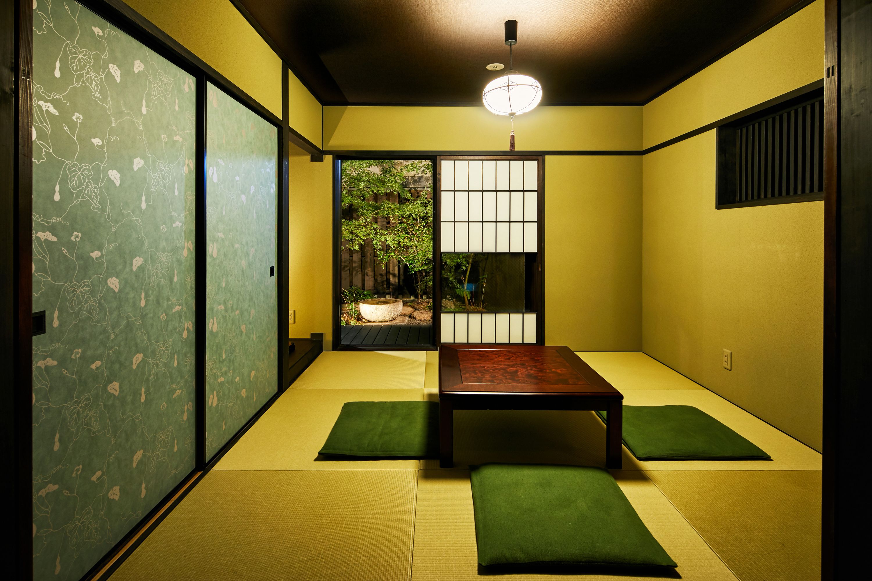 Una habitación japonesa tradicional con suelo de tatami, una mesa de madera baja y puertas correderas shoji.