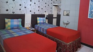A hotel room with two beds, a red and white tiled wall, a patterned wallpaper, and a small sink. - Ria Hotel Jember (Jember)
