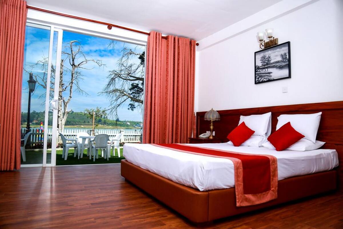 Une chambre dotée d’un grand lit, offrant une vue sur l’extérieur, et comprenant un coin repas avec des chaises et une table.