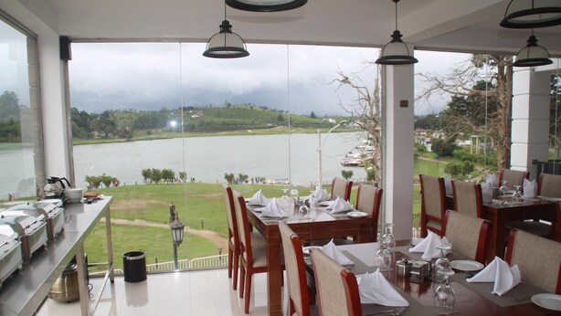 Un restaurant avec des tables et des chaises disposées pour accueillir les clients, offrant une vue sur un lac et sur le paysage environnant.