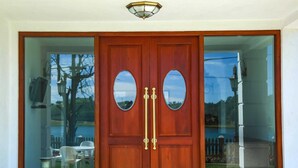 Une porte à deux battants en bois, ornée de deux miroirs ovales et dotée d’une poignée en laiton.