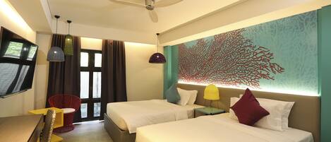 A hotel room with two beds, a desk, a chair, and a TV.