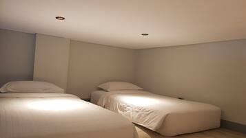 Camera da letto con due letti singoli, pavimento in legno e faretti a soffitto.