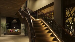 Una escalera con peldaños de madera y barandilla de metal, que baja a un nivel inferior.
