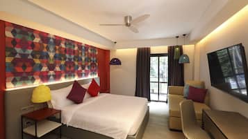 Une chambre d’hôtel moderne équipée d’un lit, d’un bureau, d’une chaise, d’un ventilateur de plafond et d’une grande fenêtre.
