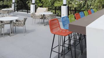 An outdoor seating area with tables and chairs, overlooking a lush green hillside.