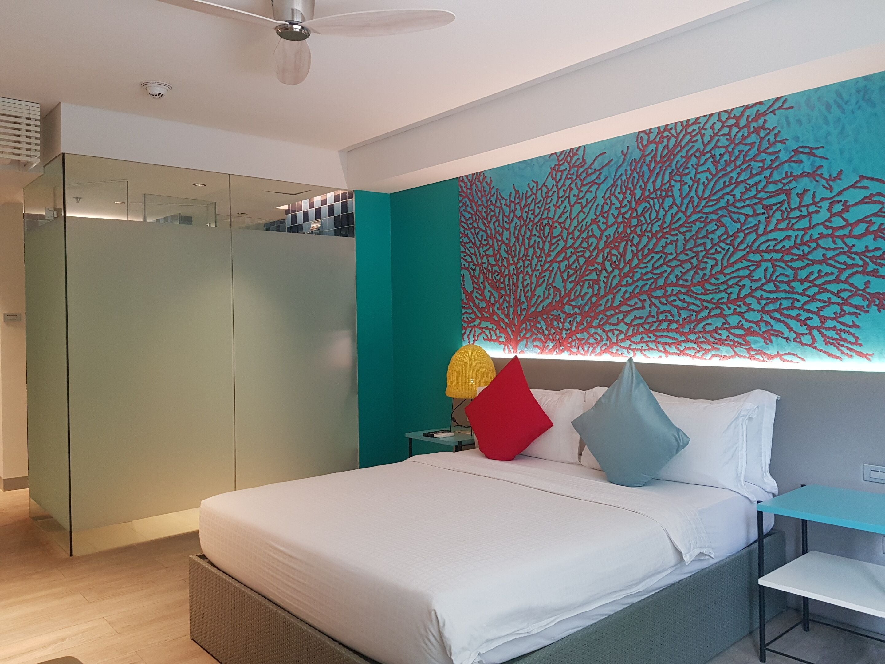 Ein modernes Schlafzimmer mit einem Bett, einem Nachttisch, einem Wandbild von rotem Korallen und einem Kleiderschrank.