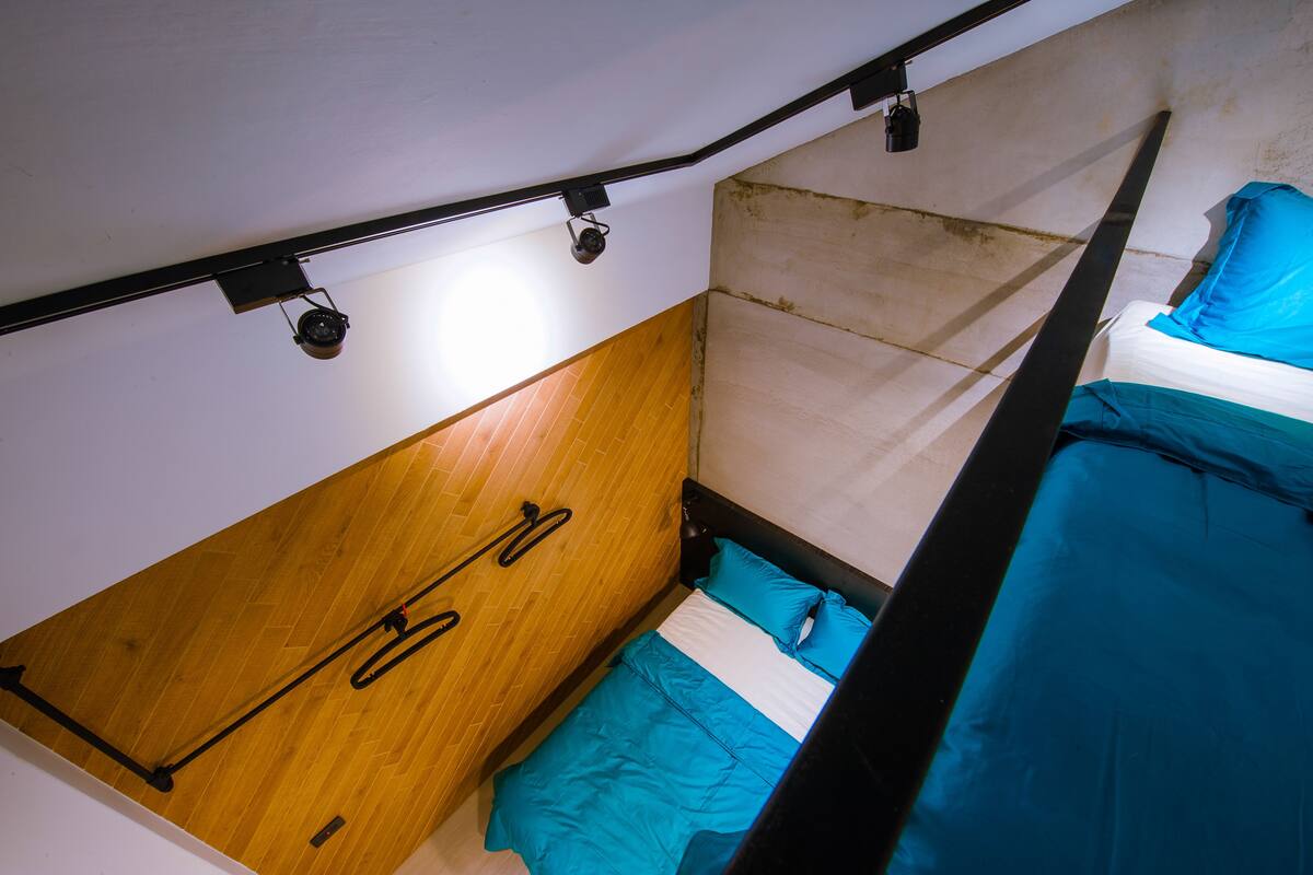 A compact room with a bunk bed, wooden paneling on one wall, and a small window.