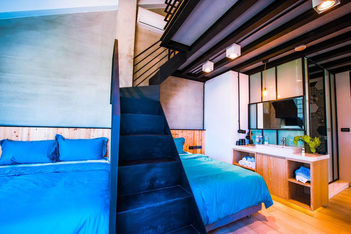 A modern bedroom with a large bed, a built-in desk, and a staircase.