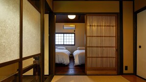 A traditional Japanese room with tatami flooring, a sliding shoji door, and a window with a view of the outside.