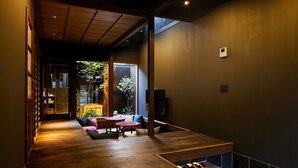 A modern interior with a wooden floor, a seating area with cushions, and a television.