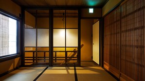 A traditional Japanese room with tatami flooring, sliding doors, and a wooden ceiling.