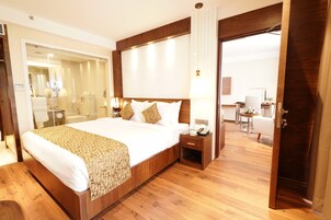 Una habitación de hotel con una cama grande, mesitas de noche, un escritorio y una silla.